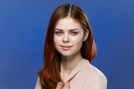 Рыжеволосая девушка с легкой улыбкой на синем фоне