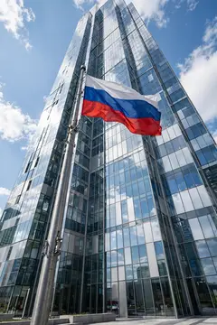 Российский флаг развевается на фоне стеклянного небоскрёба в ясный день