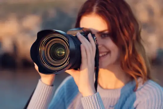 Женщина с фотоаппаратом в синем свитере в горах на открытом воздухе, обрезанный вид