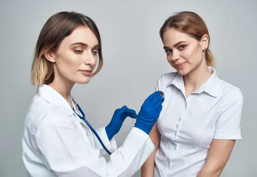 Счастливая женщина-врач в синих перчатках и пациентка в белой футболке