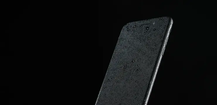 Смартфон с каплями воды на экране на чёрном фоне