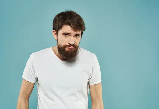 Бородатый мужчина в белой футболке на голубом фоне