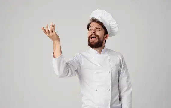 Мужчина-повар на кухне выполняет жесты руками, демонстрируя рабочие моменты на изолированном фоне