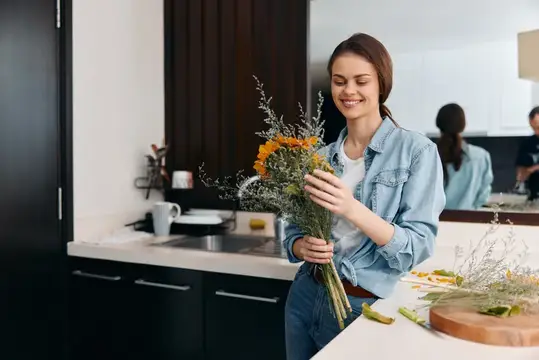 Улыбающаяся девушка с букетом полевых цветов на светлой кухне
