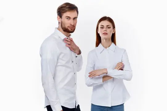 Стильные мужчина и женщина в одинаковых рубашках на светлом фоне