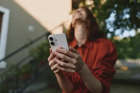 Девушка в красной рубашке держит смартфон на улице
