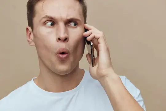 Удивлённый светловолосый парень с телефоном у уха