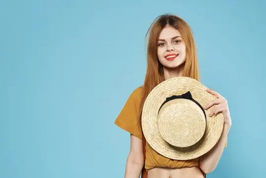 Рыжеволосая девушка с соломенной шляпой на голубом фоне