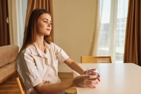 Портрет женщины, сидящей за столом со стаканом