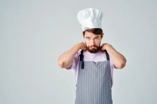 Мужчина в форме шеф-повара, его эмоции и работа на профессиональной кухне