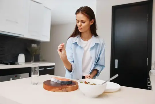 Молодая женщина готовит салат на светлой кухне