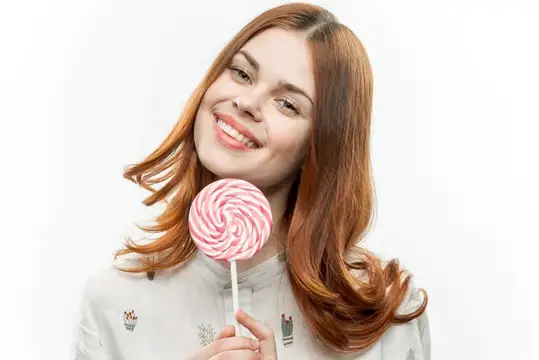 Привлекательная женщина облизывает круглый леденец, выражая радость и эмоции