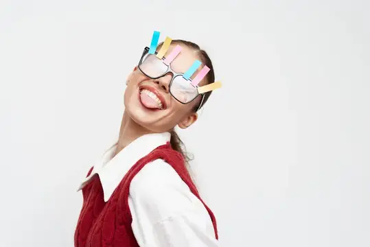 Улыбчивая девушка в очках с цветными зажимами на белом фоне