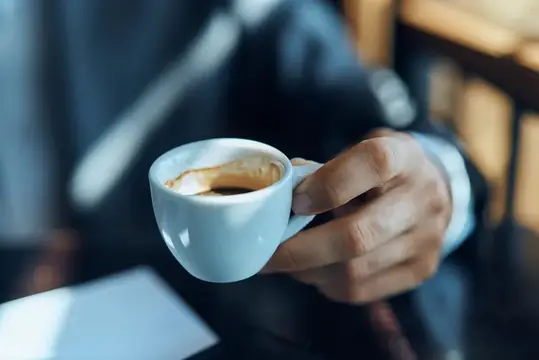 Мужская рука держит чашку кофе в кафе