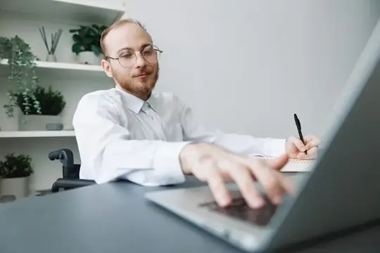 Мужчина в очках работает за ноутбуком в светлом офисе