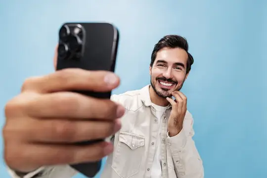 Улыбающийся бородатый мужчина делает селфи на смартфон