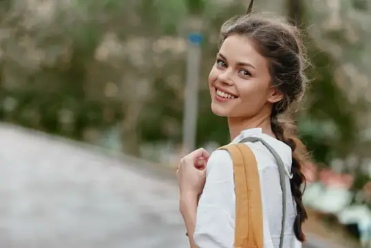 Улыбающаяся девушка с косичкой обернулась на улице