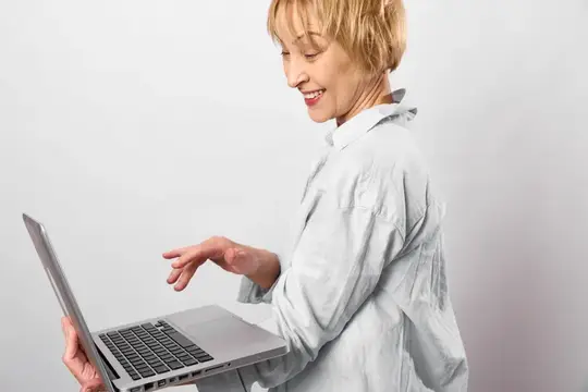 Улыбающаяся блондинка держит ноутбук на светлом фоне
