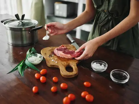 Женщина смазывает стейк соусом на кухонной доске