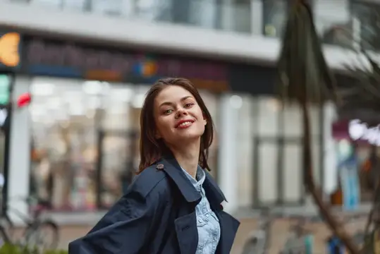 Улыбающаяся шатенка в плаще на городской улице