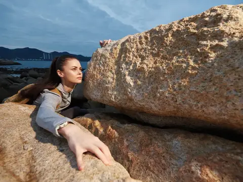 Молодая женщина лежит на больших камнях у моря
