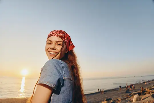 Улыбающаяся девушка в красной бандане на закатном пляже