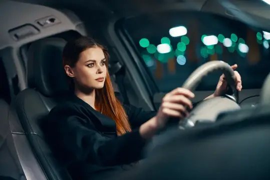 Рыжеволосая девушка за рулём автомобиля ночью