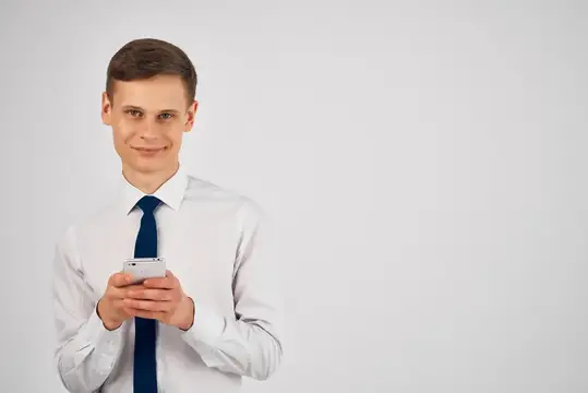 Молодой человек в белой рубашке с телефоном на сером фоне