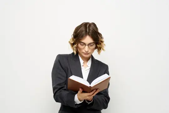 Женщина за работой с книгой в руке на светлом фоне