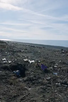 Загрязнённый пластиковыми отходами берег моря под пасмурным небом