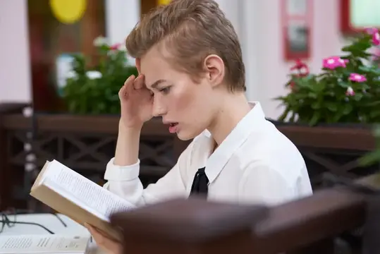Студент с книгой в руках на улице во время каникул в городе, летнее общение