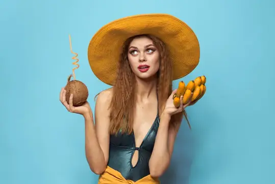 Женщина в купальнике и шляпе с экзотическими фруктами, летнее веселье на синем фоне