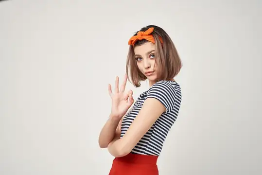 Симпатичная женщина с оранжевой повязкой на голове, модное украшение, позирует с эмоцией