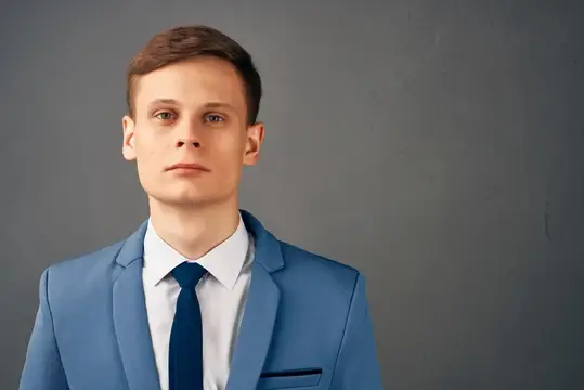 Молодой мужчина в синем костюме на сером фоне