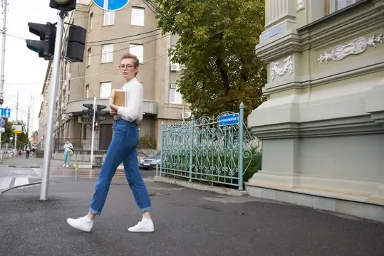 Симпатичная женщина в очках гуляет по городу с книгой в руках, посвящая время образованию