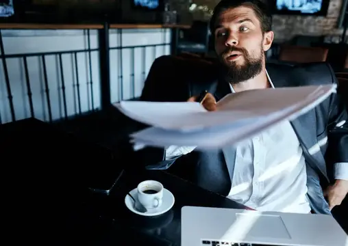 Бизнесмен в кафе в костюме перед ноутбуком, эмоции, официальные документы, технологии