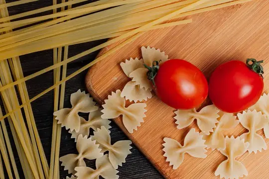 Приготовление итальянской пасты вручную на кухне с использованием помидоров черри и других ингредиентов для обеда