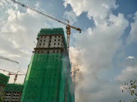 Строящаяся высотка в зелёной сетке под облачным небом
