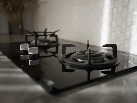 Черная газовая варочная панель с чугунными решетками на светлой кухне