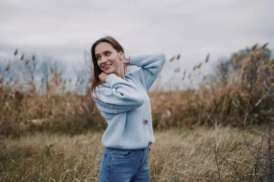 Улыбающаяся девушка в голубом свитере на осеннем поле