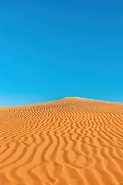 Песчаные дюны с рябью на фоне чистого синего неба