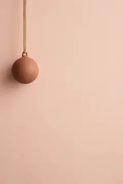 Терракотовый шар на бежевом фоне висит на шнуре