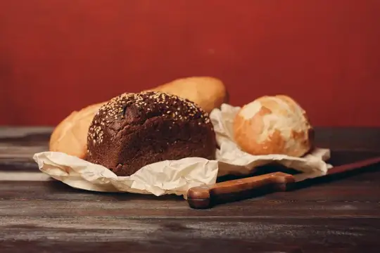 Свежий хлеб и булочки с кунжутом на деревянном столе