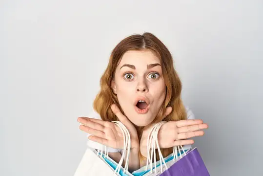 Удивлённая девушка с пакетами после шопинга