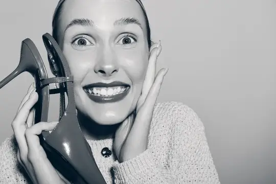 Улыбающаяся женщина с туфлями на каблуке у лица