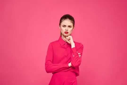 Женщина на розовом фоне в модной одежде и ярким макияжем, причёска, модель, свободное пространство