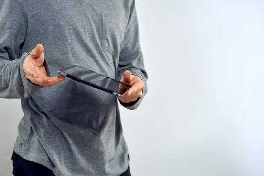 Мужчина в сером свитере держит смартфон в руках
