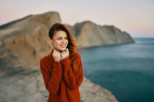 Женщина в свитере отдыхает на природе в горах, вид на океан, кадр обрезан, стиль жизни