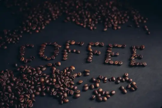 Кофейные зёрна, выложенные словом coffee на тёмном столе