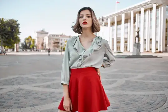 Веселая женщина в красной юбке позирует на площади на открытом воздухе